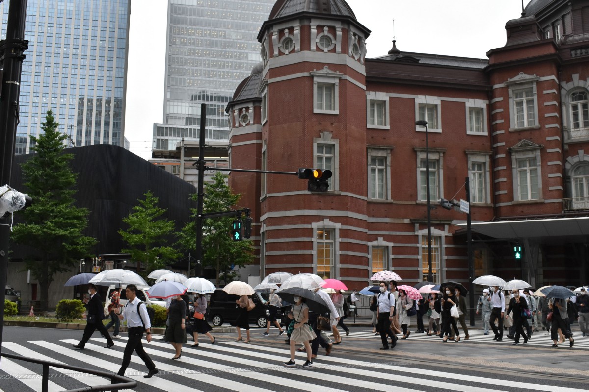 緊急事態宣言が解除されてから初の月曜日の朝を迎え、小雨の中マスク姿で通勤する人たち＝１日、東京都千代田区の東京駅前